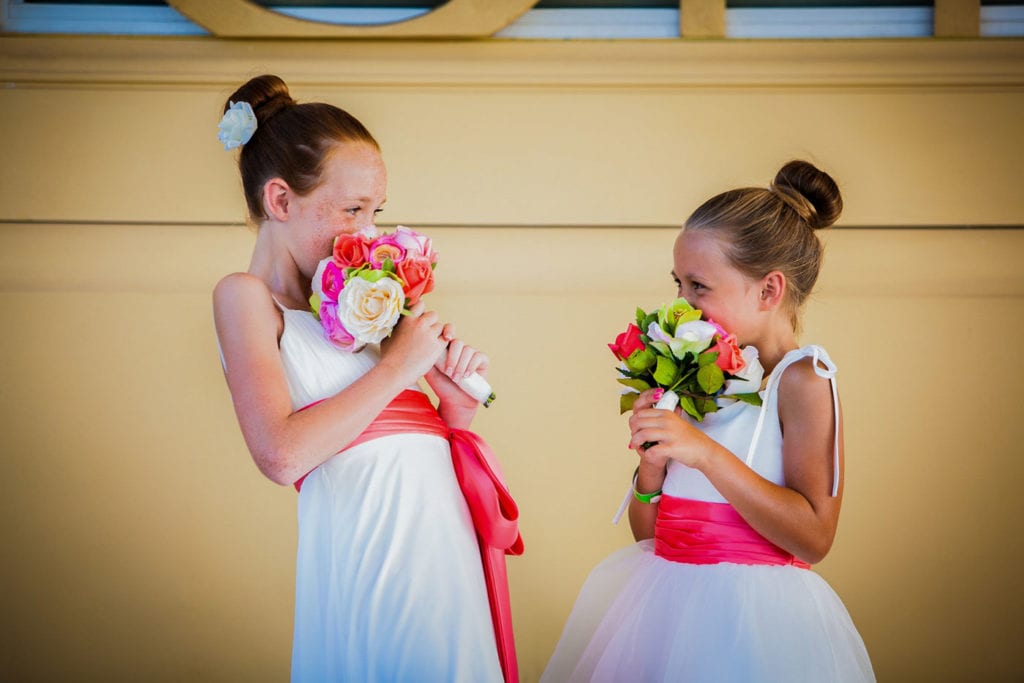 Two flower girls holding prink bouquets laugh together