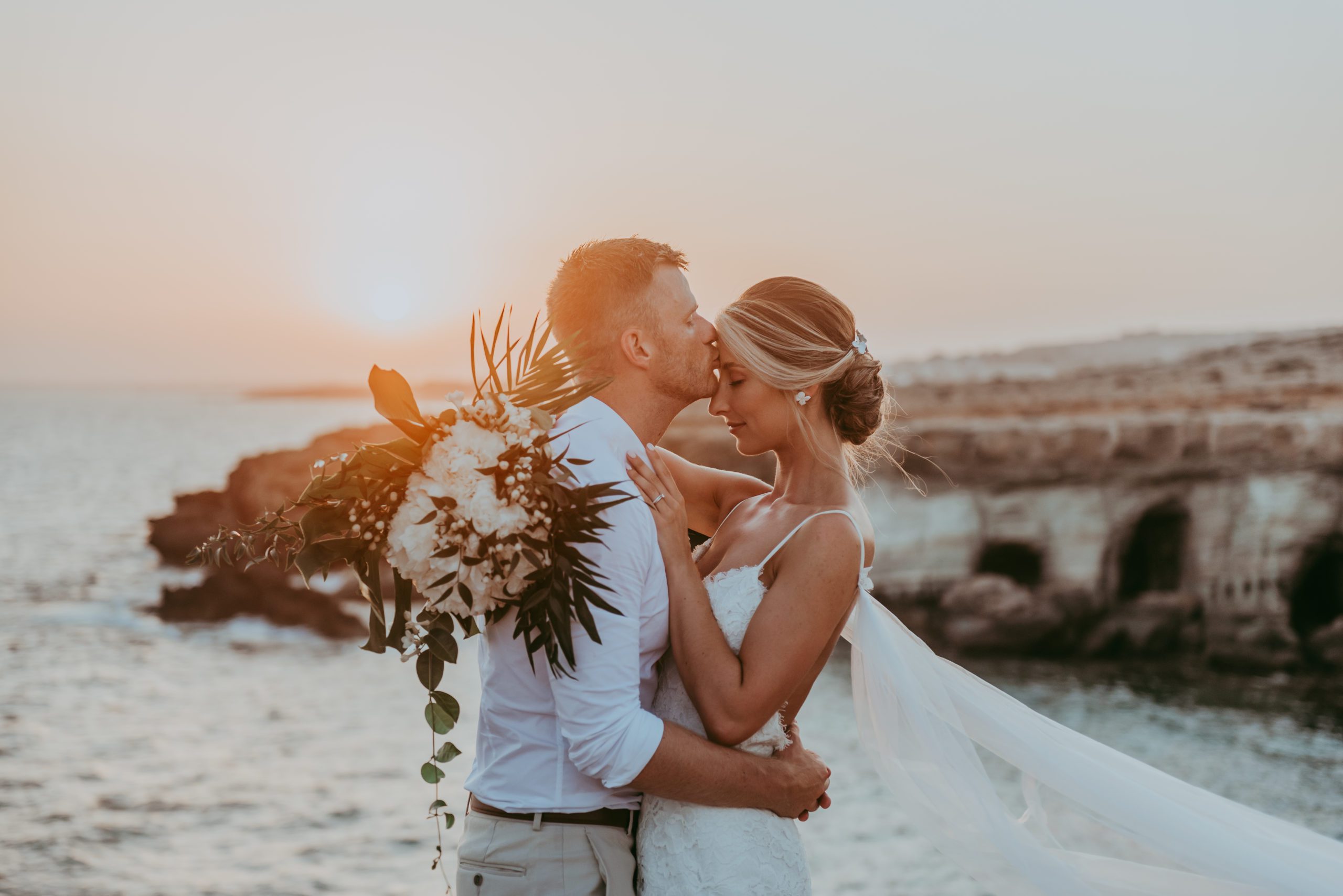 A gentle kiss as the sun sets behind the married couple